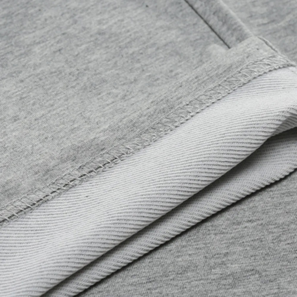 Close-up of the fabric hem and stitching detail showing the soft cotton-blend texture of the grey joggers.