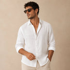 Man wearing a white linen button-up shirt open at the collar with sunglasses and beige pants