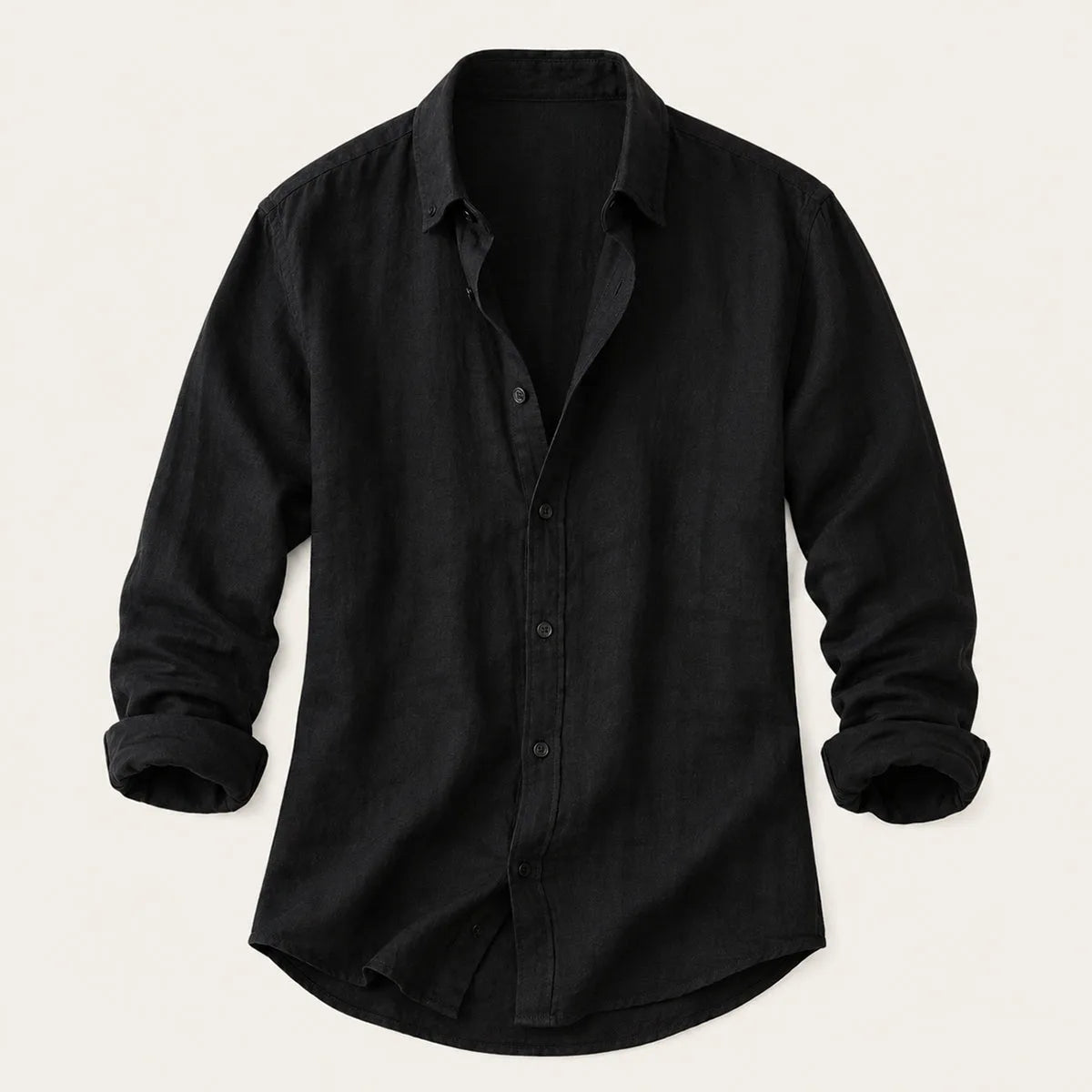 Flat lay of a black cotton-linen button-up shirt with rolled sleeves on a plain background