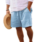 Side view of a man wearing light blue drawstring shorts with hand in pocket, cropped below the waist