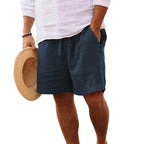 Side view of a man wearing dark navy blue drawstring shorts with hand in pocket, cropped below the waist