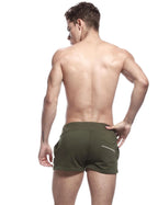 Full body front view of man wearing army green sport shorts with hands in side pockets