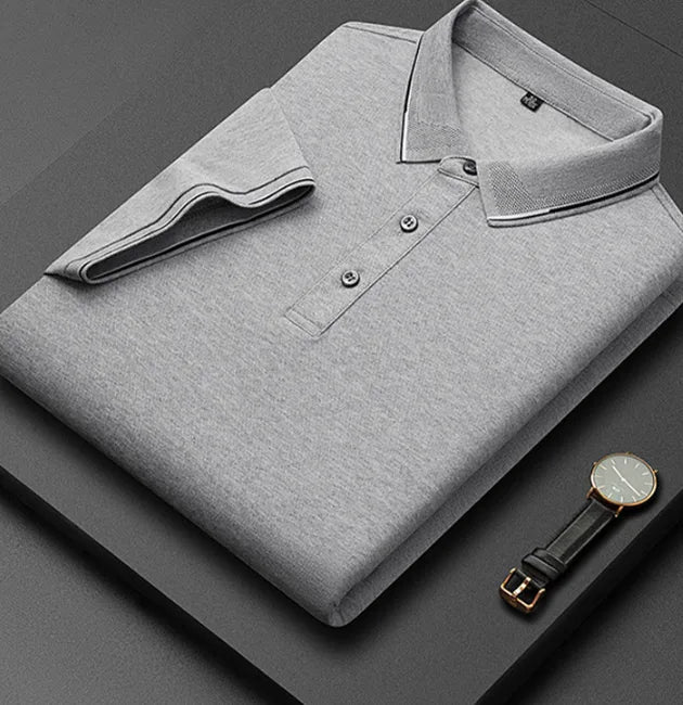 Folded light grey marle polo shirt beside a leather watch, showing soft knit texture