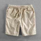 Beige linen shorts flat lay on grey background, showing fabric weave and side pocket opening