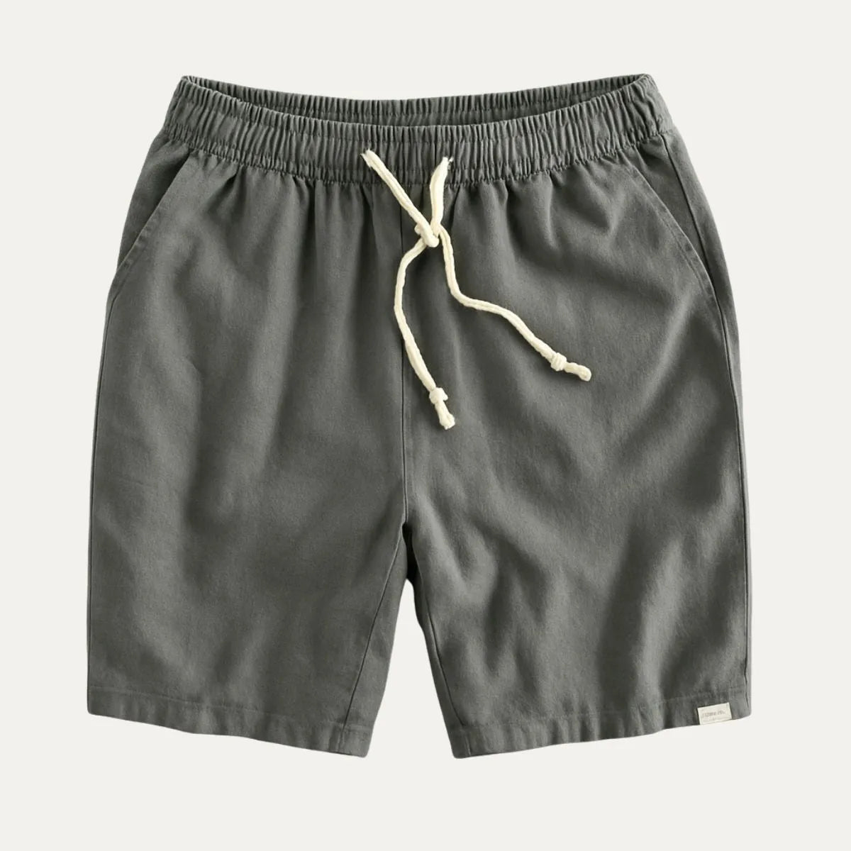 Charcoal grey drawstring shorts flat lay with visible back-pocket brand tab and cream tie cord