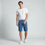 Model standing in steel blue knee-length shorts, straight-on front view with hands near waistband