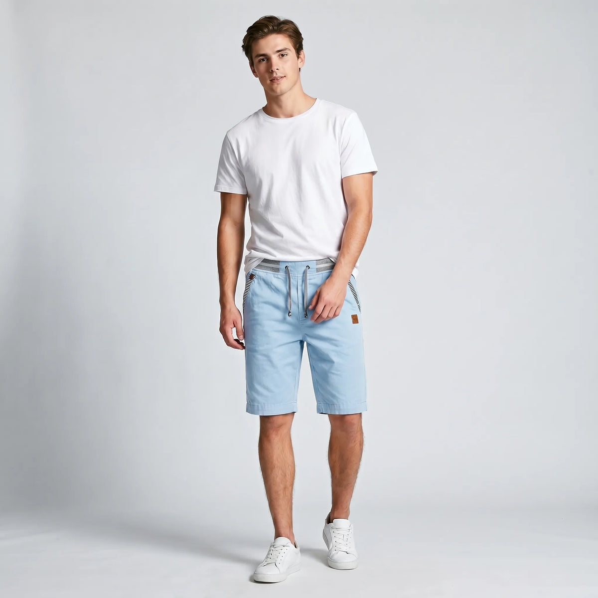 Model wearing sky blue drawstring shorts paired with a white t-shirt and sneakers, front view