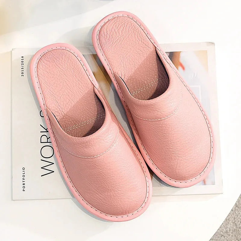 Front angle of brown leather mule slippers on feet, showing the rounded toe shape and low-profile sole.