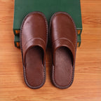 Top-down view of both brown leather slippers aligned in parallel, showing rounded toe shape and stitched vamp