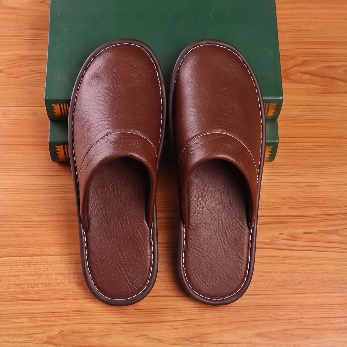 Top-down view of both brown leather slippers aligned in parallel, showing rounded toe shape and stitched vamp