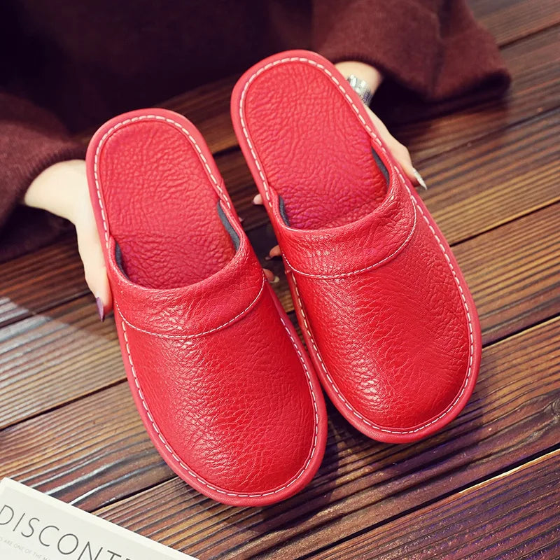 Overhead view of glossy black leather slide slippers resting on a dark wooden surface