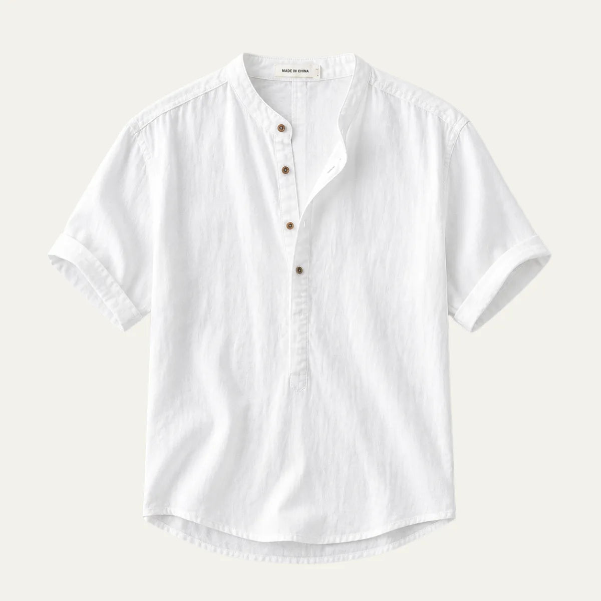 Flat lay of a white short-sleeve linen shirt with a band collar and wooden-look buttons, folded cuffs