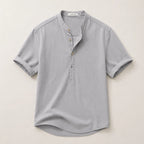 Flat lay of a grey short-sleeve linen shirt showing the collarless band neckline and folded sleeve cuffs