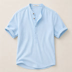 Flat lay of a light blue linen shirt showing the stand collar, button placket and curved hem