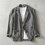 Grey linen-blend blazer worn open over a white t-shirt, showing notch lapels and a chest welt pocket