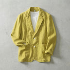 Yellow linen blazer buttoned up with rolled sleeves, showing white button detail and front patch pockets