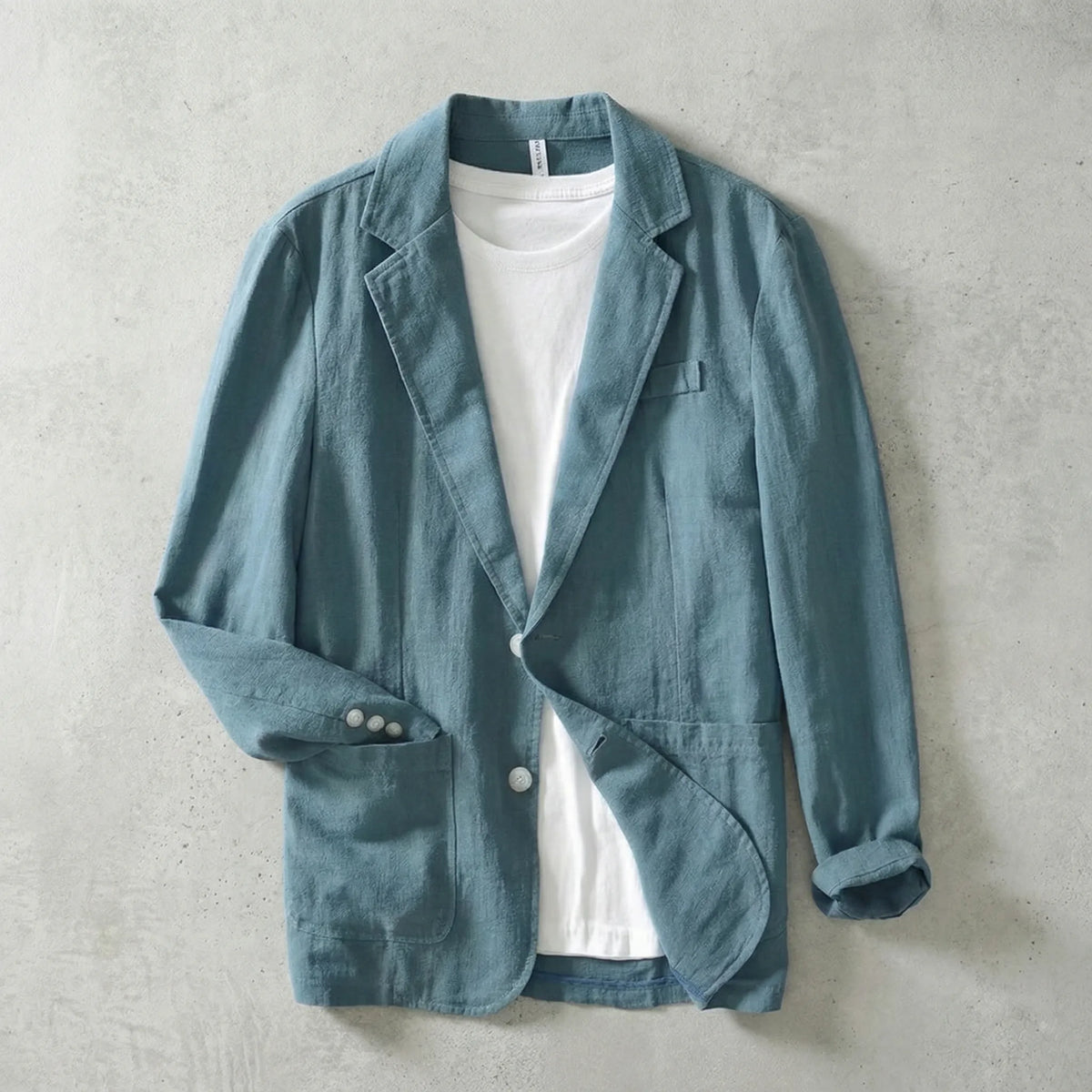Teal linen blazer buttoned with rolled cuffs, showing white buttons and dual front patch pockets