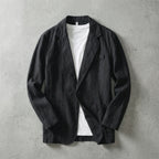 Black linen blazer laid flat and open, showing visible stitching, lapels and twin patch pockets