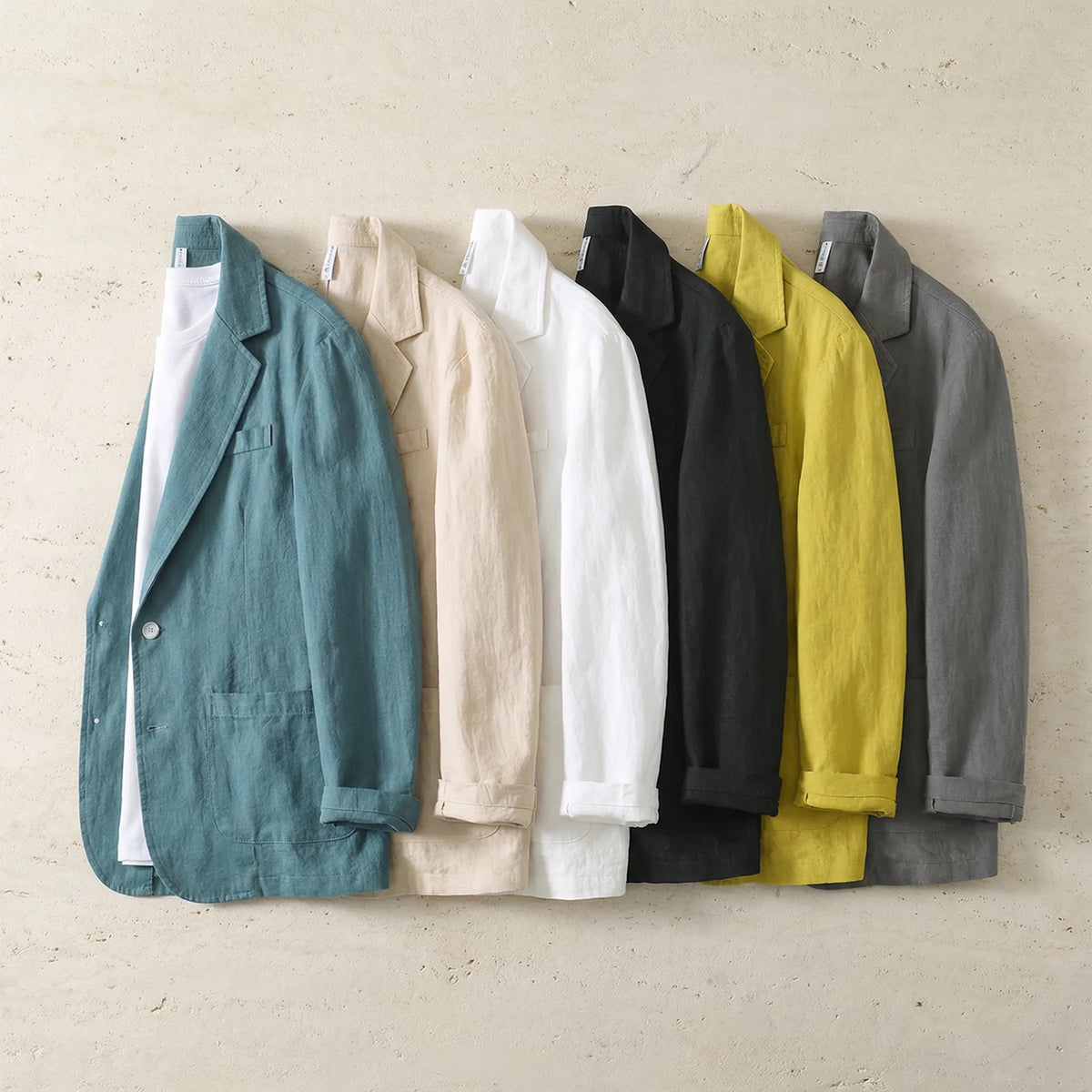 Six colourways of the linen blazer laid side by side, showing teal, beige, white, black, yellow and grey options