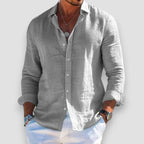 Front view of a grey linen-blend shirt, unbuttoned collar, worn open over white pants with sleeves rolled up