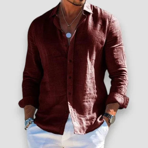 White linen-blend shirt styled open at the neck with layered necklaces and a wristwatch visible