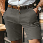 Dark grey linen-blend shorts shown from the front with button-fly detail and brown leather belt