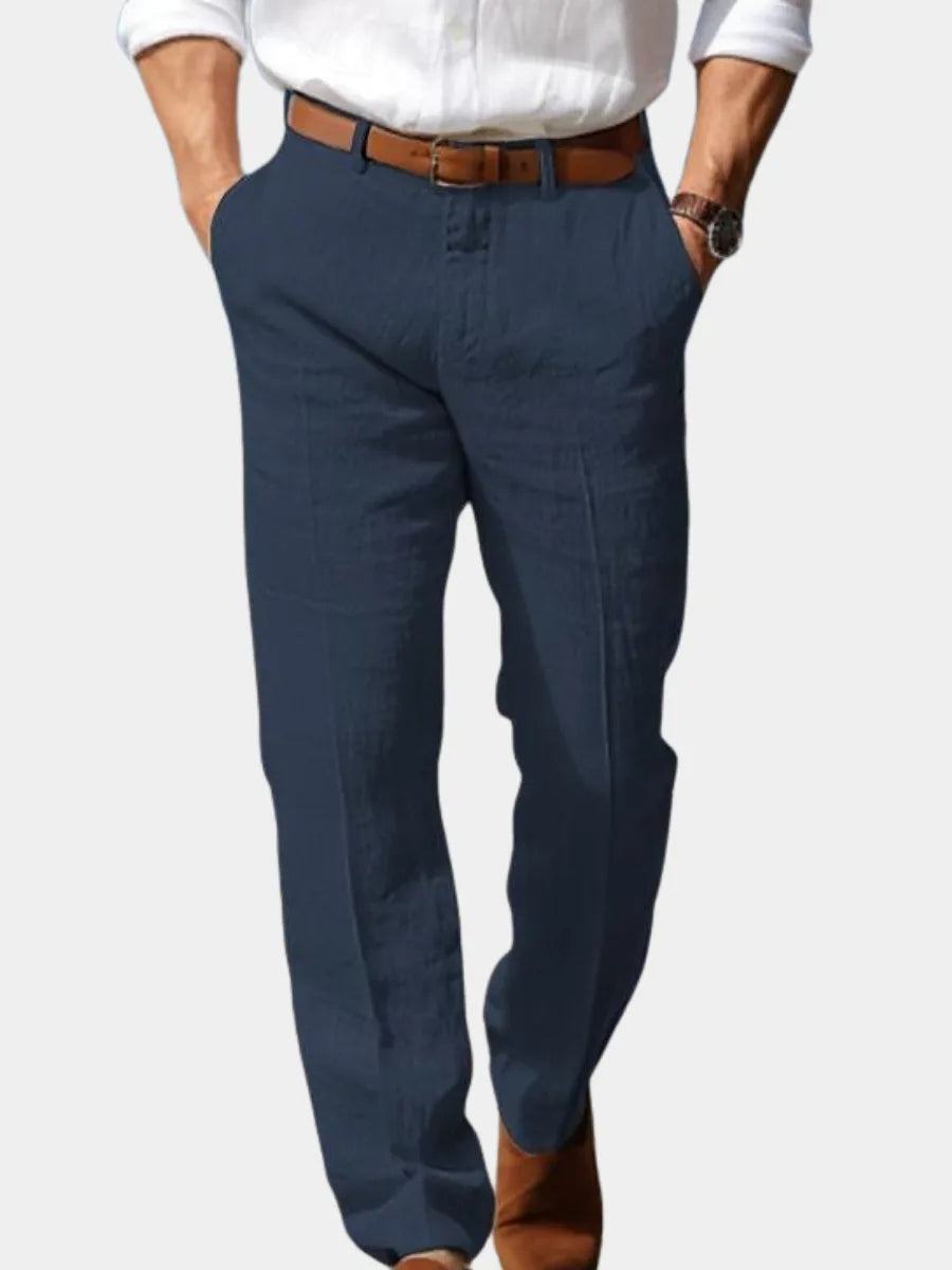 Front view of man wearing navy blue linen trousers with brown leather belt and tucked white shirt