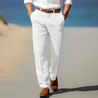 Rear view of man walking on a beach boardwalk in crisp white linen trousers with tan ankle boots
