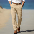 Man strolling on a beach path wearing beige linen trousers with tan suede ankle boots