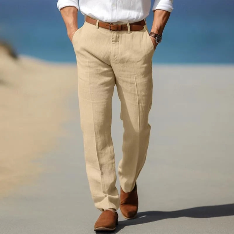Man strolling on a beach path wearing beige linen trousers with tan suede ankle boots