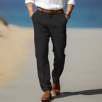 Front view of man wearing black linen trousers with brown belt, hands in pockets