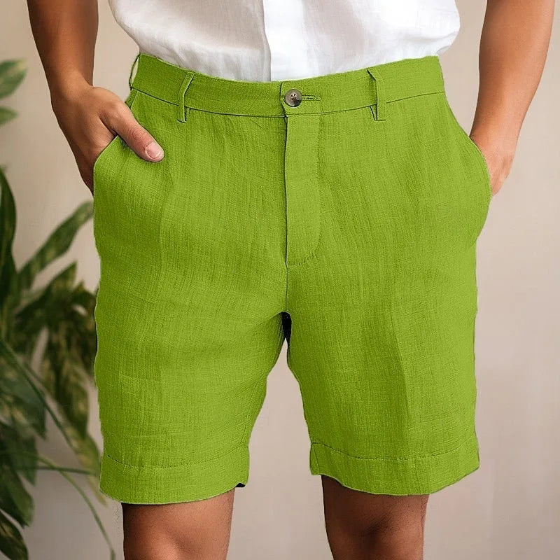 Model wearing bright olive green linen shorts with cuffed hems and front button closure