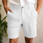 Model wearing pale grey linen shorts with button fastening, shown from the waist down against a plain backdrop