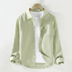 Light green linen shirt on a hanger showing the soft collar, buttoned front and chest pocket detail