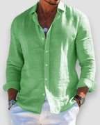 Model with hands in pockets wearing an open-collar linen shirt, showing the relaxed drape and fit