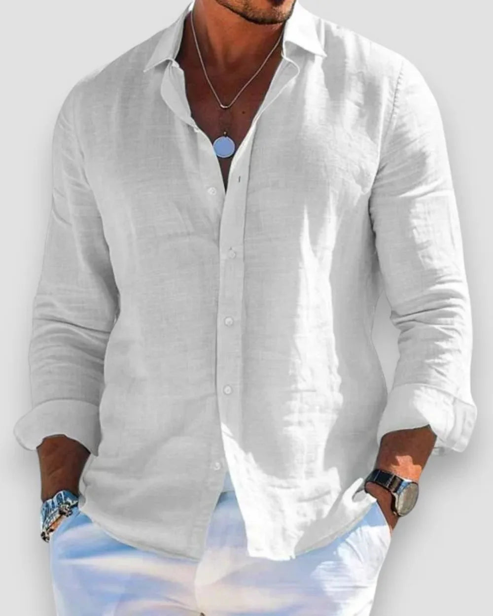White linen button-down shirt shown with sleeves rolled, worn loose over white trousers