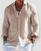 Beige linen shirt with rolled cuffs and button placket, styled with white trousers for a casual look