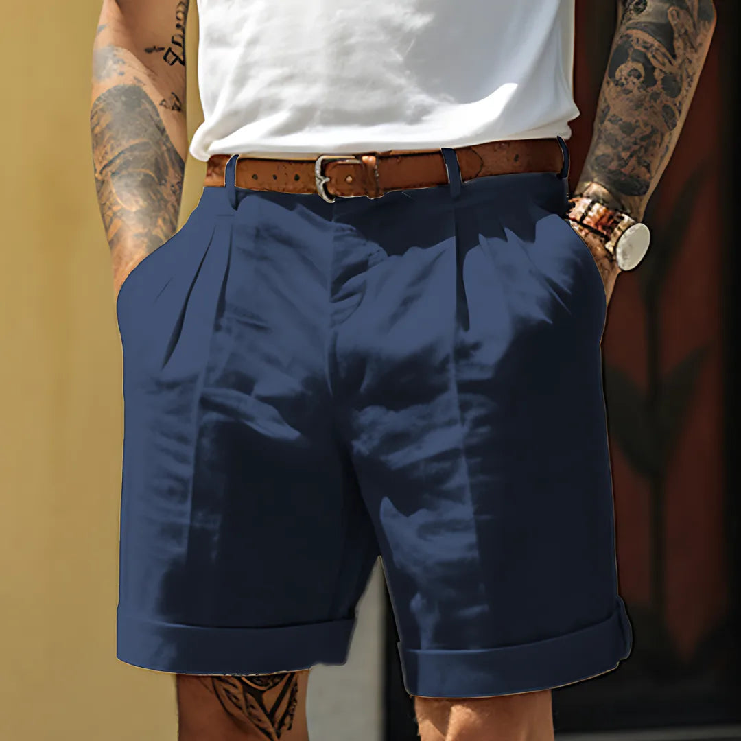 Navy tailored shorts with pleated front, belt loops and folded cuff hem, close-up front view