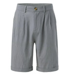 Flat lay of grey tailored shorts showing button fastening, belt loops, pleats and cuffed hem