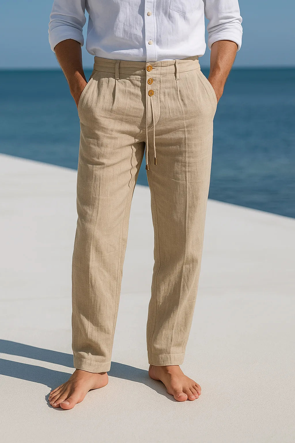 Close-up front view of beige linen pants with wooden buttons, belt loops and drawstring waist tie
