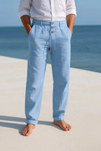 Light blue linen trousers with rolled hems, worn barefoot, showing the tapered leg and soft drape