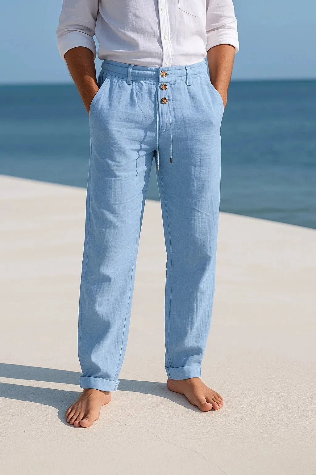 Light blue linen trousers with rolled hems, worn barefoot, showing the tapered leg and soft drape