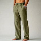 Side view of olive green linen drawstring trousers showing relaxed fit and raw-hem ankle length