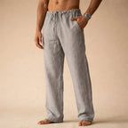 Close front view of grey linen trousers with drawstring tie and hand in side pocket