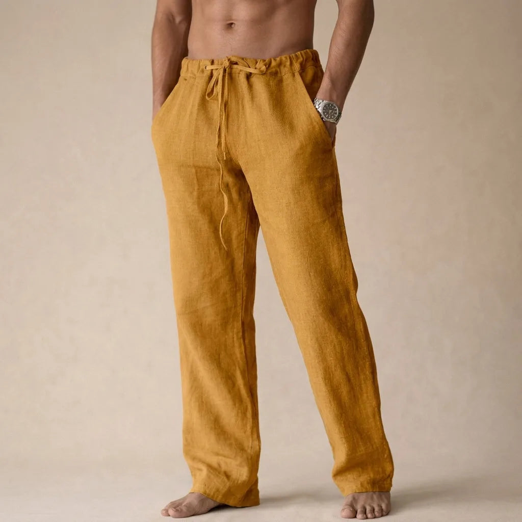 Front view of mustard gold linen trousers with drawstring waist and hands in pockets