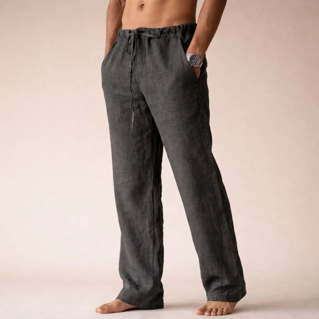 Side view of dark grey linen pants showing straight leg drape and raw hem finish