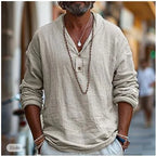 Man wearing a khaki linen popover shirt with V-neck, shawl collar and two-button placket, layered necklaces visible.