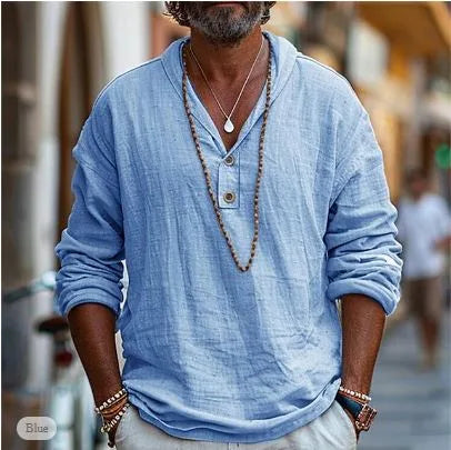 Close-up of a light blue linen popover shirt with long sleeves and textured woven fabric, worn with beaded bracelets.
