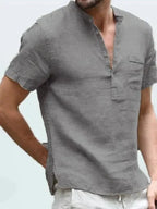 Side angle of a grey linen short sleeve shirt showing the stand collar, chest pocket and relaxed fit on a male model.