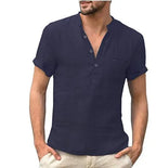 Man wearing a navy blue linen short sleeve shirt with open collar and chest pocket, hand in pocket.